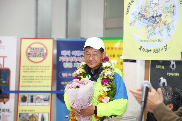 15일 강원도 동해항에 입국한 강명구 평화 마라토너는 환영행사 참석자들로부터 꽃다발을 받았다. (사진제공: 평마사)