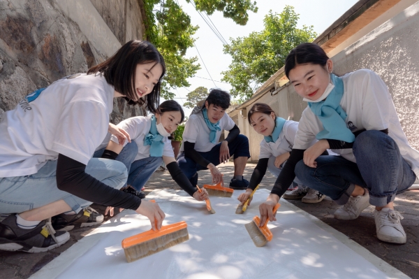 지난 25일 대우건설 대학생 홍보대사들이 서울시 성북구에 위치한 노후주택에 도배할 벽지에 풀을 바르고 있다. (사진=대우건설)