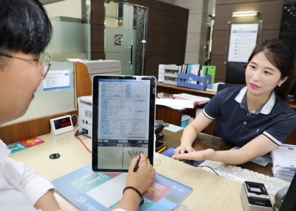 Sh수협은행 직원이 고객에게 태블릿PC로 전자신청서를 작성하는 것을 돕고 있다. (사진제공=수협은행)