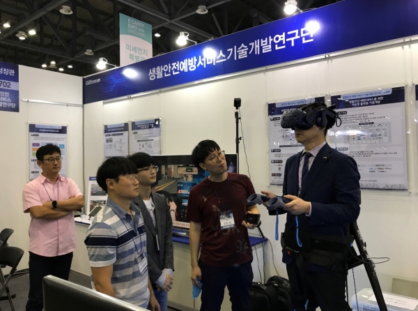 권승준 ETRI 선임연구원이 VR 헤드셋을 쓰고 화재 시 소화기 사용 방법을 체험할 수 있도록 설명하고 있다. (사진제공=ETRI)