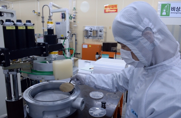 ETRI 연구진이 질화갈륨 전력소자 칩의 제작공정 중 반도체 웨이퍼를 들고 있다. (사진제공=ETRI)