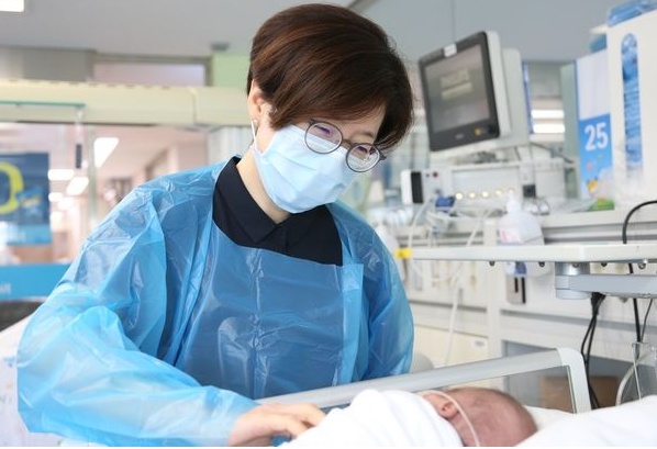신생아실 김이경 교수가 심장수술을 받고 퇴원을 기다리는 온이를 바라보며 미소를 짓고 있다.(사진: 서울대병원)