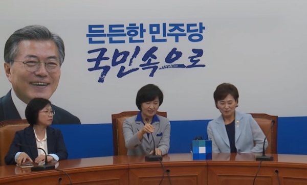 김현미(오른쪽) 국토교통부 장관과 추미애(가운데) 법무부장관이 나란히 앉아있는 가운데 왼쪽에는 문재인 대통령의 웃는 모습의 사진이 그려진 백드롭이 인상적이다. (사진=더불어민주당 아카이브 캡처)