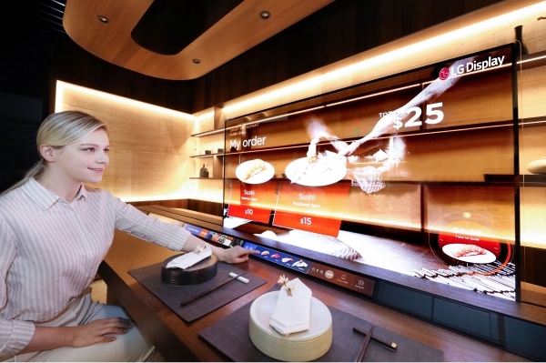 LG디스플레이가 'CES 2021'에서 선보이는 레스토랑 존에서 모델이 투명 OLED를 이용해 메뉴를 살펴보고 있다. (사진제공=LG디스플레이)