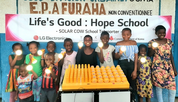 프라하(Furaha) 초등학교 학생들이 LG전자가 설치한 친환경 태양광 충전시스템 '솔라카우'를 이용해 충전한 휴대용 보조 배터리를 사용하며 기뻐하고 있다. (사진제공=LG전자)