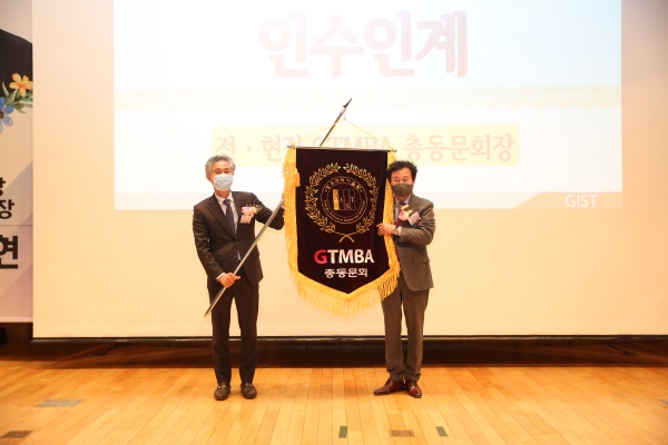 (왼쪽)정기섭 제4대 총동문회장이 송경현 제3대 총동문회장으로부터 GTMBA 깃발을 인계받고 있다.