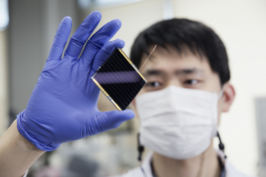 UNIST 연구자가 페로브스카이트 태양전지를 들어보이고 있다. (사진제공=UNIST)