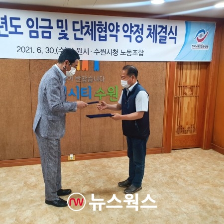 김기배 환경국장(왼쪽)이 김성복 노동조합위원장과 협약서를 교환하고 있다(사진제공=수원시)