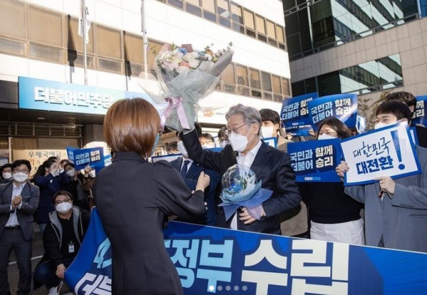이재명 민주당 대선후보가 민주당 대선후보로 확정된 후 서울 여의도 민주당 중앙당사를 찾았다. 민주당사 앞에서 한 여성 지지자로부터 축하의 꽃다발을 받고 있다. (사진=이재명 후보 인스타그램 캡처)