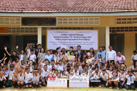 지난 7일 캄보디아 프놈펜에서 진행된 기부 물품 전달식에서 KB국민카드 현지법인인 KB대한특수은행 임직원들과 운롱깐초등학교 아이들이 기념촬영을 하고 있다. (사진제공=KB국민카드)