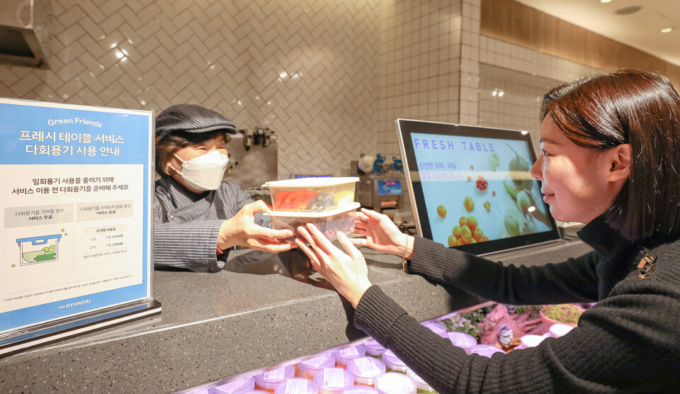 서울 강남구에 위치한 현대백화점 무역센터점 지하 1층 식품관 '프레시 테이블'에서 직원이 손님에게 다회용기에 담긴 상품을 전달하고 있다. (사진제공=현대백화점)