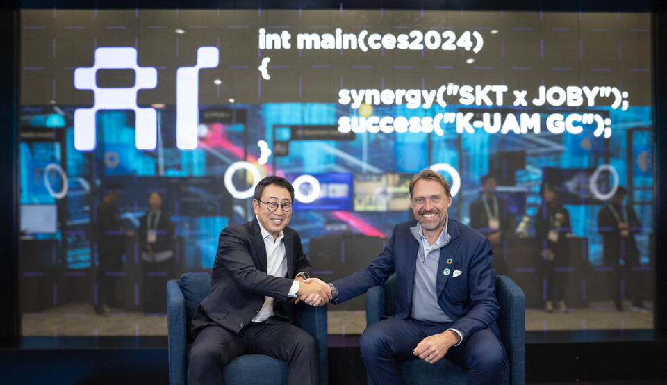 유영상(왼쪽) SKT 대표와 조벤 비버트 조비 에비에이션 CEO가 CES 2024에 마련된 ‘SK ICT 패밀리 데모룸’에서 회동하며 악수하고 있다. (사진제공=SK텔레콤)