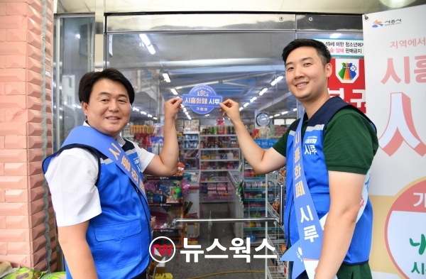 임병택(왼쪽) 시흥시장이 시흥화폐 '시루' 가명점 스티커를 붙이고 있다. (사진제공=시흥시)