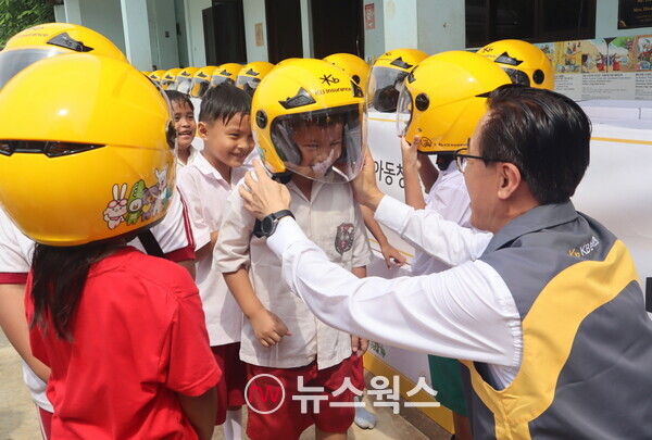 조정래 KB손해보험 인니법인장이 Sinar Cahaya Kasih 학교 학생들에게 안전모를 씌워주고 있다. (사진제공=KB손해보험)