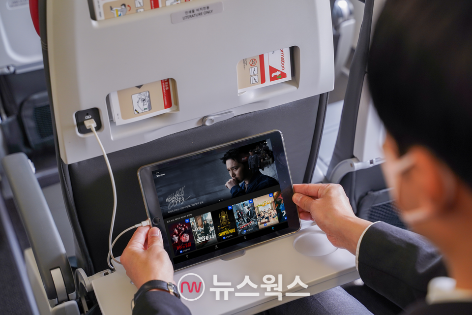 티웨이항공 승객이 기내에서 OTT 플랫폼 서비스 '웨이브'를 개인 스마트 기기로 감상하고 있다. (사진제공=티웨이항공)