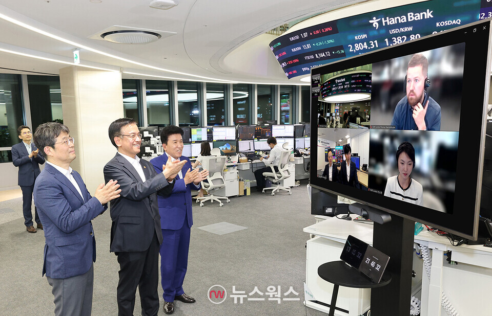 외환시장 개장 시간 연장 첫날을 맞아 최상목(왼쪽 두 번째) 부총리 겸 기획재정부 장관, 유상대(왼쪽 첫 번째) 한국은행 부총재, 함영주(왼쪽 세 번째) 하나금융그룹 회장이 하나은행 딜링룸을 방문해 하나은행 런던 지점 및 스테이트스트리트은행(SSBT) 런던 지점과 화상 연결 종료 후 현지 직원들을 격려하고 있다. (사진제공=하나은행)