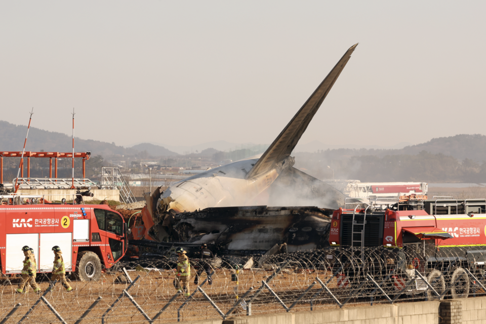 29일 오전 9시 7분경 전남 무안국제공항 활주로에 여객기가 추락해 사고 수습이 이뤄지고 있다. 울타리 콘크리트벽과의 강한 충돌로 기체가 폭발하면서 꼬리 부분만 형체를 유지하고 있다. (사진=뉴스1)