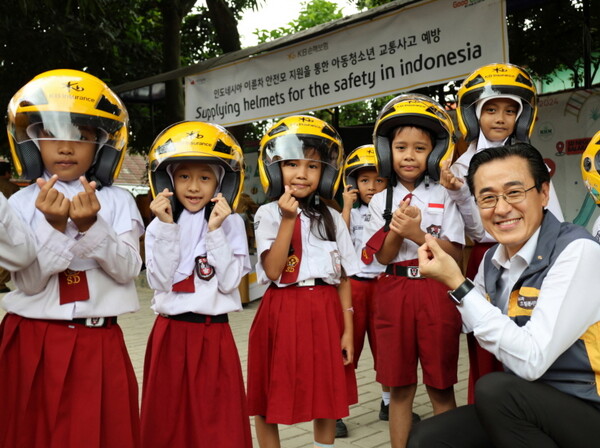 조정래(오른쪽) KB손해보험 인니법인장이 지난 11일 인도네시아 발라라자(Balaraja) 초등학에서 진행한 '이륜차 안전모 전달식'에서 안전모를 전달받은 학생들과 기념 촬영을 하고 있다. (사진제공=KB손해보험)