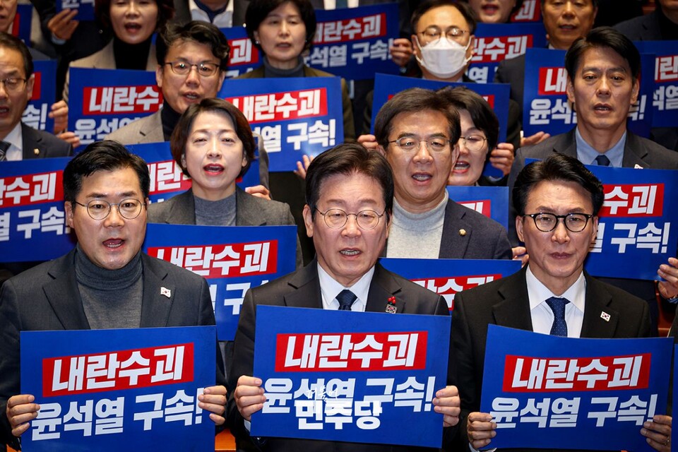 이재명(앞줄 가운데) 민주당 대표와 민주당 의원들이 지난 27일 국회에서 열린 '의원총회'에 참석해 '내란수괴 윤석열 구속'이라고 쓰인 손팻말을 들고 구호를 외치고 있다. (사진제공=민주당)