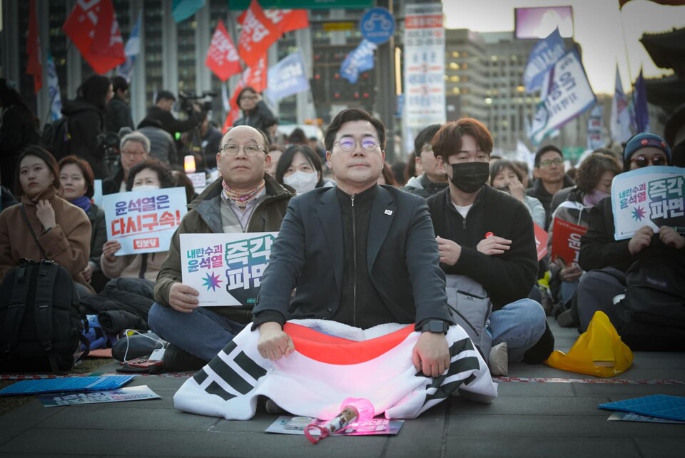 박찬대 민주당 원내대표가 14일 서울 광화문 삼거리에서 열린 '최고위원회의'에서 태극기를 덮고 전면을 응시하고 있다. (출처=박찬대 원내대표 페이스북)