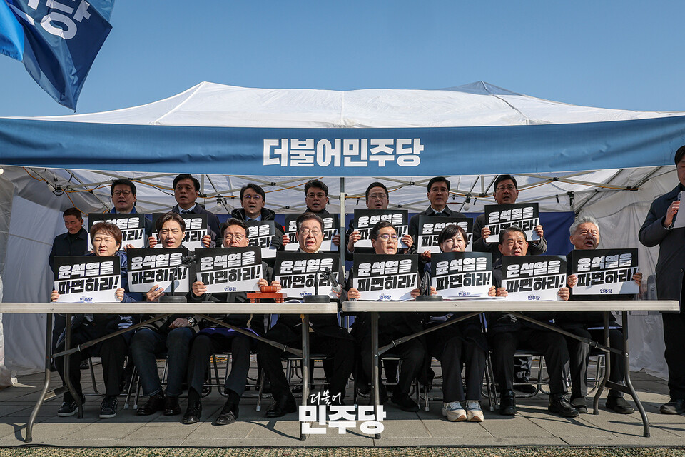 이재명 더불어민주당 대표가 19일 서울 종로구 광화문 인근의 더불어민주당 천막농성장에서 열린 현장최고위원회의에 참석하여 피켓을 들고 구호를 외치고 있다. (출처=더불어민주당 홈페이지)