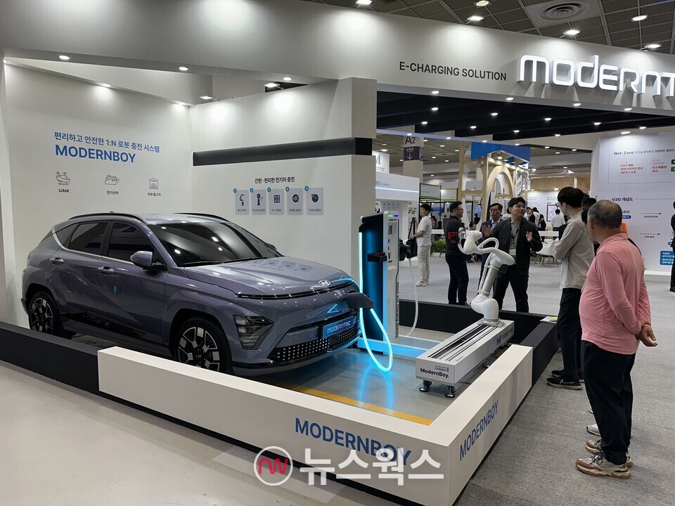 관람객들이 '모던텍' 부스에 전시된 로봇 충전 시스템 '모던보이'에 대해 관계자로부터 설명을 듣고 있다. (사진=정현준 기자)
