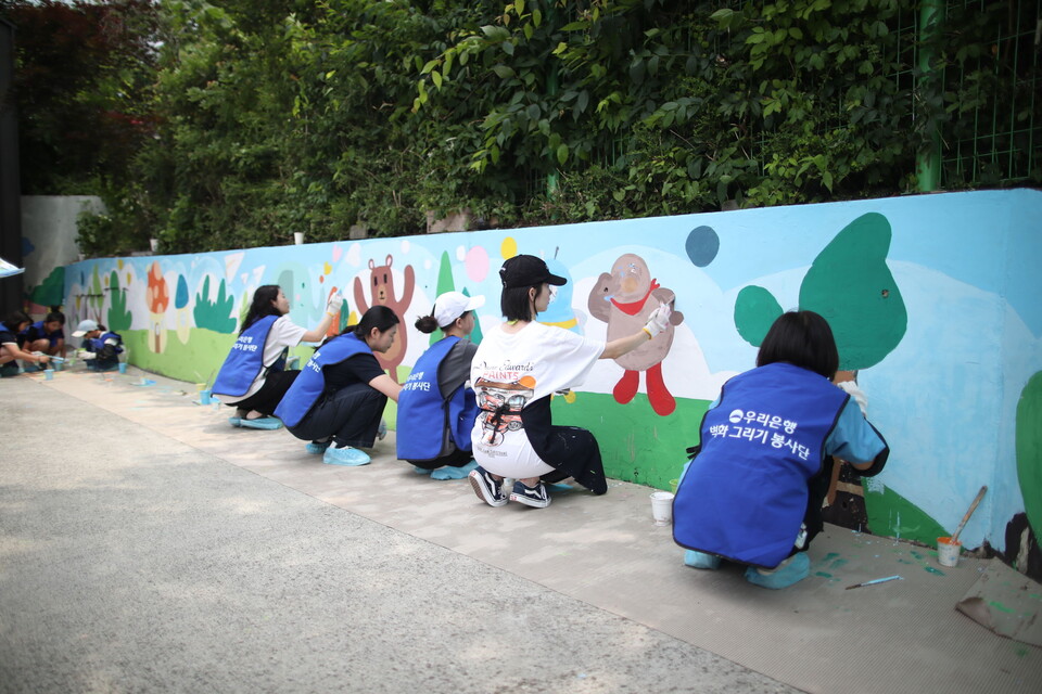 우리은행 임직원과 가족들이 참여하는 'WOORI 가족봉사단'이 서울·경기·부산·대전 등 4개 지역에서 벽화그리기 봉사활동을 전개했다. (사진제공=우리은행)