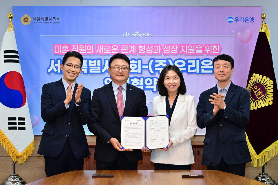 최호정(오른쪽 두 번째) 서울시의회 의장과 조세형(왼쪽 두 번째) 우리은행 부행장이 지난 9일 결혼 친화적 조직문화를 확산하기 위해 지속적으로 협력한다는 내용이 담긴 협약서를 들어보이고 있다. (사진제공=서울시의회)