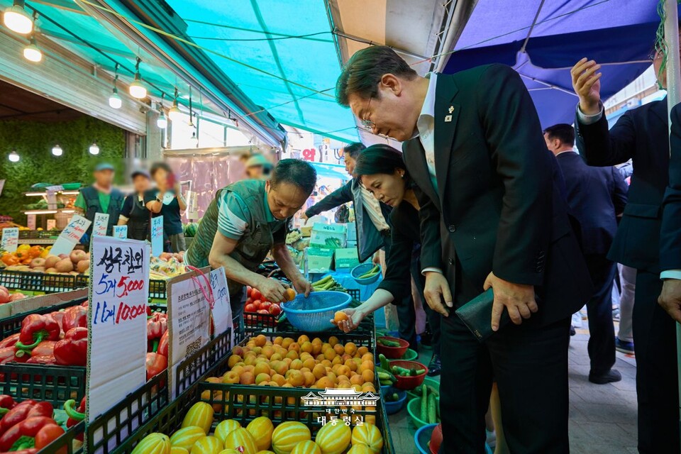 이재명 대통령과 부인 김혜경 여사가 지난 6월 6일 현충일 추념식 참석 직후 서울 동작구 사당동의 남성사계시장을 방문해 과일을 구매하고 있다. (출처=대통령실 홈페이지)