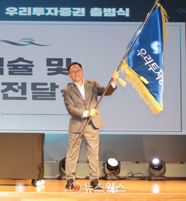 남기천 우리투자증권 대표가 지난해 8월 1일 열린 출범식에서 회사기를 흔들고 있다. (사진제공=우리투자증권)